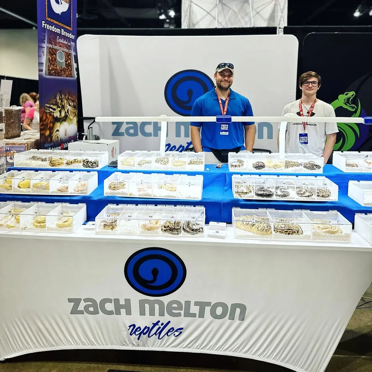Two vendors behind rows of clear enclosures at their booth