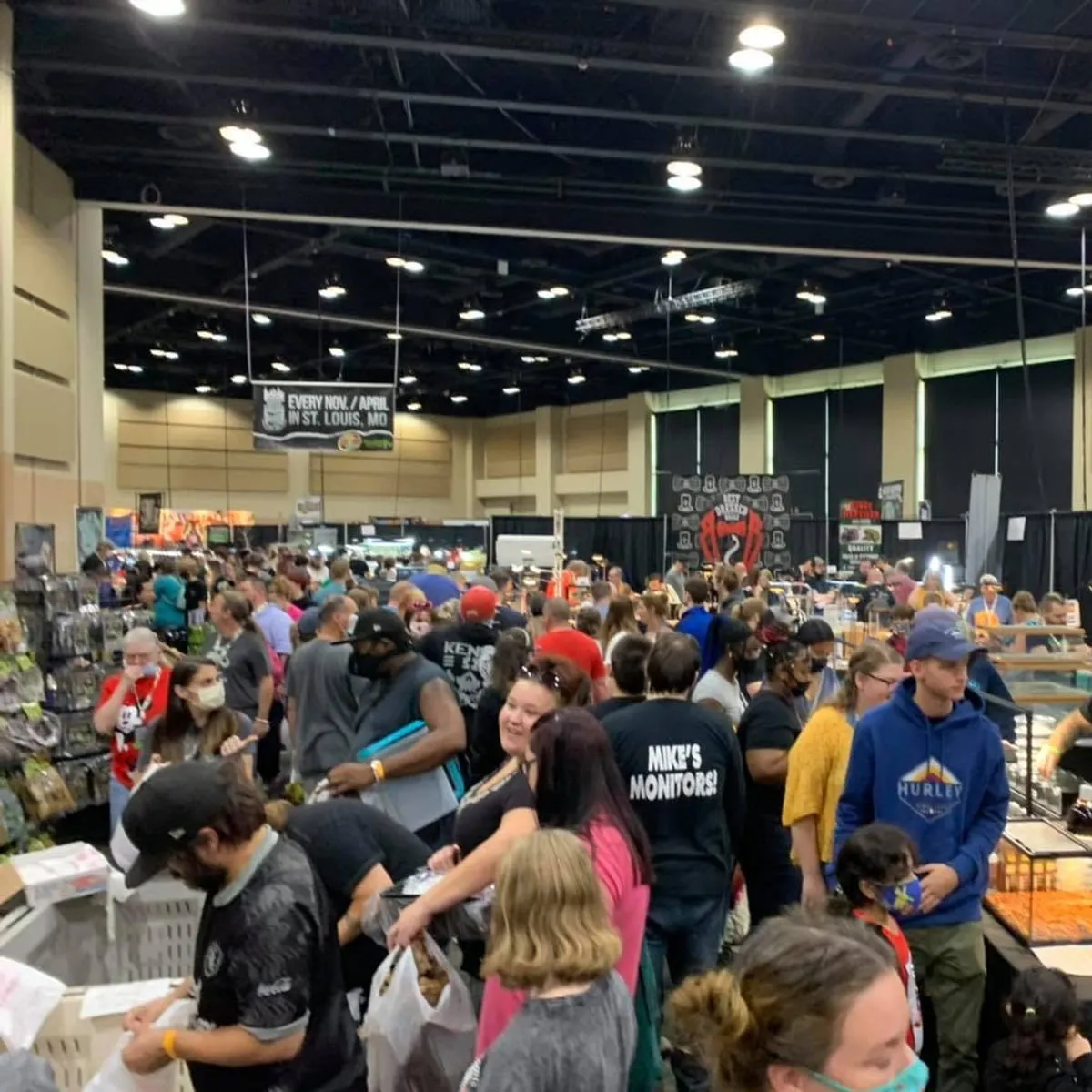 A crowded vendor aisle with shoppers lined along both rows of tables