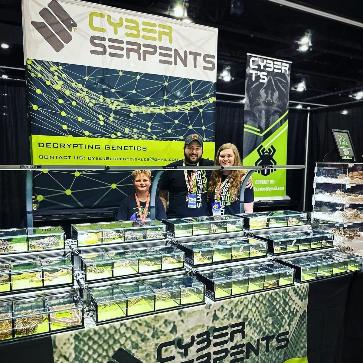 A lit rack of enclosures at a breeder's booth, the vendors behind it